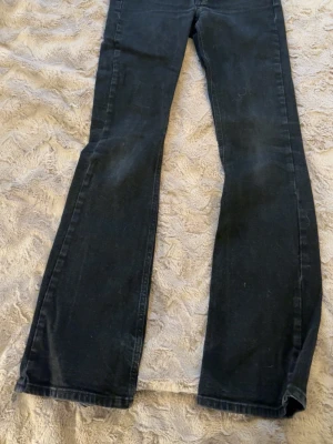 Svarta bootcut jeans från Junkyard XS - Svarta jeans från Junkyard i bootcut-modell med klassisk femficksdesign och knappstängning. Jeansen har en något utsvängd passform nertill och är tillverkade i jeansmaterial. 