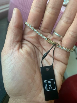 Snö of Sweden armband ! - Armbandet består i grunden av s925. Det är i sin tur doppat i 18k guld. Resten av armbandet är täckta av jämnstora cubic zirconia. Stenar med ett vackert spänne.  Vid stängning av länken som ger armbandet ett väldigt lyxigt och exklusivt lyft. Spännet märkt ’’Snö’’ -prislapp kvar kostar ca 800 i butik   Först till kvarn   Se gärna min profil för mera fint och bra grejer till bästa priserna. Behöver ni något som inte finns ute på annons är det bara att slänga iväg ett SMS  0700588783 