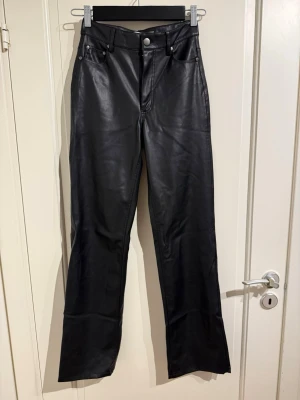 Vida svarta skinnbyxor - Svarta skinnbyxor som är högmidjade och vidare i benen.