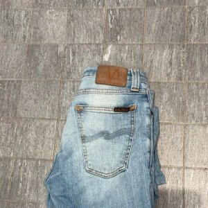 Ljusblå jeans från Nudie Jeans W27 L32 - Säljer ett par ljusblå jeans från Nudie Jeans. Slim fit.                                                                       Som har INTE använts mycket. PRIS:400kr.         STORLEK: 27-32 