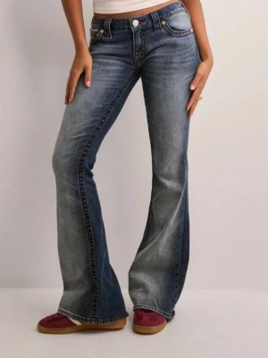 True Religion bootcut jeans blå - Säljer ett par snygga blå bootcut jeans från True Religion med klassisk röd kontrastsöm och ikonisk logga på bakfickan. Jeansen har normal passform, fem fickor och är tillverkade i slitstarkt denimmaterial. Perfekt för dig som gillar retrovibbar och coola detaljer.