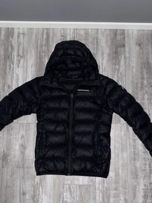 Svart Peak Performance dunjacka - Svart Peak Performance jacka med huva. Den är i bra skick. Använd ett par gånger men den är väl omhändertagen. 