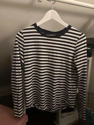 Randig långärmad topp - Jag säljer en långärmad svartrandig tröja, den har inget märke tyvärr så vet inte var den är ifrån. Den är väldigt fin och säljs för att den inte har används. Storleken är oklar men den passar bra på mig som vanligtvis är en storlek S i tröjor 
