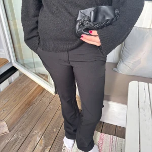 Svarta lågmidjade bootcut kostymbyxor - Säljer ett par svarta kostymbyxor med bootcut-snitt. Byxorna har en klassisk passform med lätt utsvängda ben och low waist. Perfekta för dig som vill ha en stilren och clean look. Materialet känns mjukt och följsamt💞