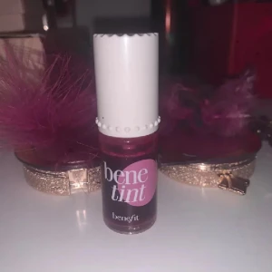 Benefit Benetint röd tint - Benetint från Benefit är en flytande tint i röd nyans som kan användas både som rouge och läppfärg. Kommer i en liten glasflaska med vit skruvkork och applikator. Perfekt för en naturlig, rosig look.
