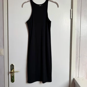 Svart ärmlös klänning från Bik Bok - Supersnygg svart klänning från Bik Bok med stilren, rak passform och ärmlös design. Klänningen har hög halsringning och är tillverkad i mjukt, stretchigt material som sitter bekvämt. Perfekt för dig som gillar minimalistisk stil och vill ha en enkel men chic look.