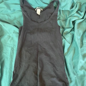 Svart baslinne från H&M i bomull - Enkel svart linne från H&M Basic i mjuk bomull. Linnet har klassisk rund halsringning och ärmlös design, perfekt att matcha med jeans eller shorts. Snyggt och stilrent plagg som funkar året runt.