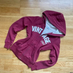 Vintage Y2K zip up med foder  - Mysig vinröd hoodie med dragkedja och mjuk fodrad insida – perfekt för kalla dagar. Trycket ”Vintage 1962” framtill ger en unik retro vibe och gör den enkel att styla till både vardag och streetwear. 	•	Storlek: S 	•	Färg: Vinröd 	•	Bra skick, sparsamt använd 	•	Rare modell – inte lätt att få tag på  En perfekt höstfavorit 🍁 som både är varm och trendig!