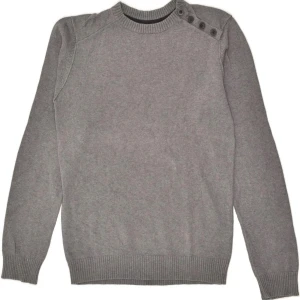 Grå stickad tröja från Jules - En stilren grå stickad tröja från Jules med rund halsringning och snygga knappar på ena axeln. Tröjan har ribbade muddar vid ärmslut och nederkant, vilket ger en clean och modern look. Storlek M men passar även S