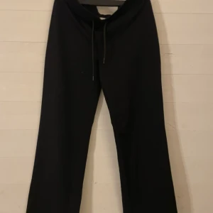 Svarta mjukisbyxor med snörning - Svarta mjukisbyxor med rak passform och snörning i midjan. Byxorna är tillverkade i mjukt bomullsmaterial och har en enkel, stilren look som passar perfekt för chill dagar. Klassisk design utan synliga loggor eller detaljer.