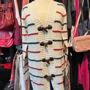 Randig kofta från Rut m.fl. med knäppning - Snygg lång kofta från Rut m.fl. i stickad bomull med breda ränder i marinblått och rött på en vit bas. Koftan har grova träknappar och bred ribbad kant framtill. 