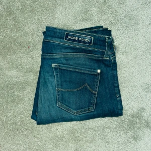 Jacob Cohën blå slim jeans - Snygga blå jeans från Jacob Cohën med klassisk femficksdesign och broderad logga på fickan. Inga tecken på slitage! Jeansen har en slim passform och är tillverkade i mjukt bomullsmaterial med lätt stretch. Besvarar frågor. Inga byten