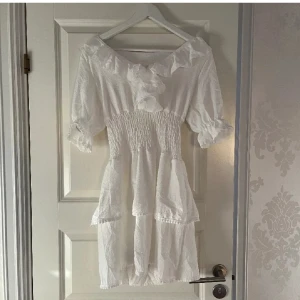 Vit klänning - Superfin vit kortklänning med smockad midja, volangdetaljer och puffärmar, passar perfekt till studenten eller skolavslutning, endast använd vid 2 tillfällen😊🌸