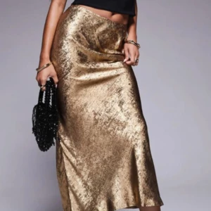 Guldig långkjol i satin-look - Säljer en glansig långkjol i guld med snygg satin-finish.