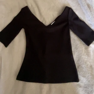 Svart v-ringad topp med trekvartsärm - Svart v-ringad tight t shirt från hm. Ny utan prislapp!💞