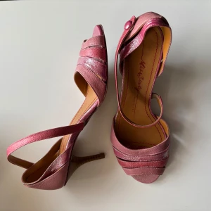 Rosa pumps från Miss Sixty i skinn - Snygga rosa pumps från Miss Sixty med glansiga detaljer. Skorna har öppen tå, smal klack och en elegant rem med knapp över vristen. Perfekta för dig som vill sticka ut med en feminin och trendig look. Enormt bra skick!!