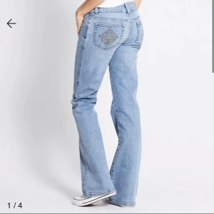 Ljusblå bootcut jeans med broderi - Snygga ljusblå jeans med bootcut passform och låg midja. Jeansen har ett detaljerat broderi i guldtråd på bakfickan och klassisk femficksdesign. Perfekta för dig som gillar en avslappnad men trendig stil. Har haft på mig ett par gånger, bättre än bra för priset. 