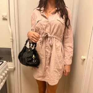 Ljusrosa SkjortKlänning med knytning  - Säljer en ljusrosa skjortklänning med knappar framtill och knytbälte i midjan. 😍 Så snygg till höga stövlar nu på hösten! Förlåt att jag inte strök den hahah men den är sååå fin man känner sig som Bianca Ingrosso lol ⭐️Använd en gång! Fraktar/Möts upp i Solna. Kolla min profil för mer kläder <3 Paketpris gäller! 