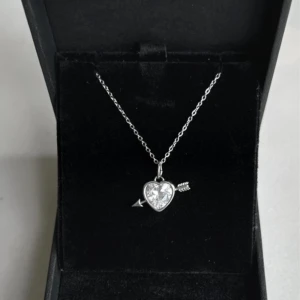 Halsband - Snyggt halsband i silverfärg med ett gnistrande hjärta och en pil genom. Jätte fint och perfekt till alla tillfällen💓