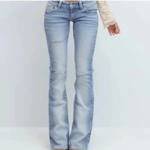 Ljusblå bootcut jeans med broderi - Snygga ljusblå bootcut jeans med slitningar på låren och knäna. Bakfickorna har broderade detaljer och små pärlor som ger extra stil. Jeansen har låg midja och klassisk femficksdesign. Perfekta för dig som vill ha en trendig och unik look.