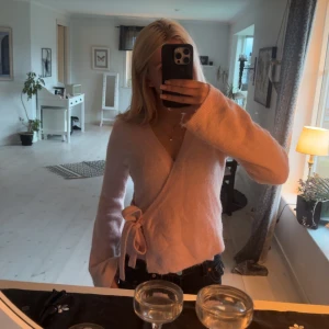 Ljusrosa omlottkofta med knytband - Supermysig ljusrosa omlottkofta med knytband i sidan och v-ringad hals. Koftan är från Gina tricot, pyttelite nopprig men absolut inge man tänker på strlk xs/s