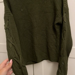 Olivgrön stickad tröja med snörning - Säljer en olivgrön stickad tröja med flätade ärmar!!!