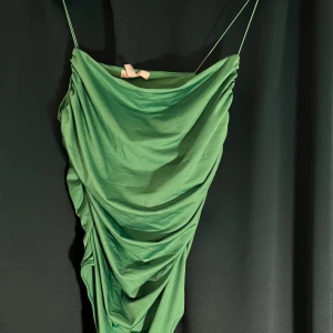 Grön draperad bodysuit H&M - Snygg grön body  från H&M med tunna axelband och draperad effekt framtill.  