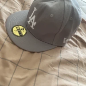 LA keps i färgen grå  - Säljer en helt ny LA keps i färgen grå i storleken 7 3/8 alltså 58,7 cm brett säljer för 500kr 