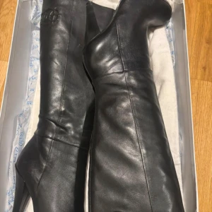 Svarta höga stövlar från Guess - Snygga svarta stövlar från Guess i äkta skinn med hög klack. 