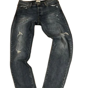 Jack & Jones slitna jeans comfort fit - Priset ej hugget i sten! Dm för fler frågor!    Mörkblå jeans från Jack & Jones med slitna detaljer och snygga slitningar på benen. Modellen är comfort fit och har klassisk femficksdesign. Jeansen är tillverkade i denim och har en avslappnad passform som ger en cool och avslappnad look.