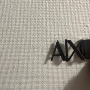 Svart AX skärp med metallspänne 100cm - Snyggt svart bälte från Armani Exchange med ett stilrent metallspänne i form av AX-loggan. Bältet är gjort i slätt skinn och har en modern, minimalistisk look som passar till jeans eller kostymbyxor.