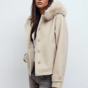Beige ulljacka med fuskpäls-krage - Beige jacka i ullmix med stor fluffig fuskpäls-krage och knappar framtill. Jackan har raka ärmar med dekorativ knappdetalj vid ärmslut och två fickor fram. Perfekt för dig som vill ha en stilren och mysig look under kyliga dagar. Helt ny jacka med etikett på storlek L och den passar mig perfekt som har xs s