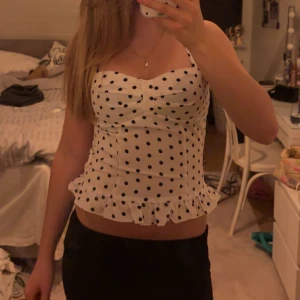 Vit prickig korsett med volangkant - Supersöt vit korsett-topp med svarta prickar och volangkant nertill. Snygg sweetheart-urringning och breda axelband. Pris kan diskuteras, skriv om du har frågor 💕