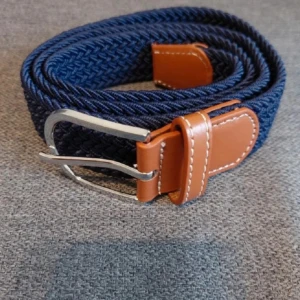 Marinblå flätat bälte - Snyggt marinblått flätat bälte med detaljer i brunt skinn och silvrigt spänne. Bältet har en cool struktur och passar perfekt till jeans eller chinos. De bruna skinnpartierna har vit söm som ger en schysst kontrast mot det mörkblå materialet.