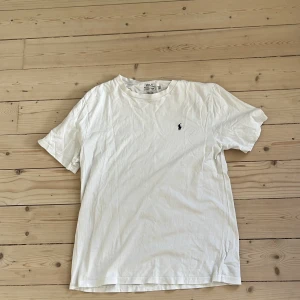 Vit t-shirt från Polo Ralph Lauren  - Vit t-shirt från Polo Ralph Lauren i storlek XL BARN ( passar s vuxen) Klassisk modell med korta ärmar och rund hals. Broderad marinblå logga på bröstet. Tillverkad i mjuk bomull . 