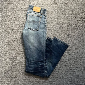Blå jeans från Nudie Jeans - Nudie jeans med sjukt snugga slitningar både fram och bak. De har blivit lagade på ena knät och under byxan som man ser på de två sista bilderna. Storlek 30/34