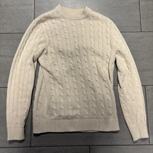 Beige stickad tröja, Selected Homme - Kabelstickad beige tröja från Selected Homme med rund halsringning och ribbade muddar. Tröjan har lång ärm och klassisk kabelmönstrad design, perfekt för dig som gillar en stilren och enkel look. Testats en gång så precis som ny. Pris kan diskuteras. 
