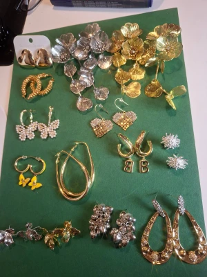 Mix av statement örhängen i guld & silver - Säljer ett stort set med trendiga örhängen i olika former och stilar. Här finns blommiga statementörhängen i både guld och silver, hjärtformade örhängen med glittriga stenar, örhängen med bokstaven B, pärlbeströdda fjärilar, samt coola hoops och örhängen med gula fjärilar. Perfekt för dig som vill variera din look!