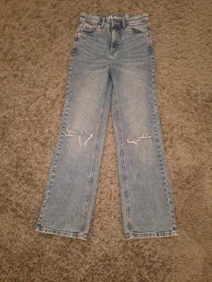 Blå wide jeans från LAB Industries - Snygga ljusblå jeans från LAB Industries med raka, wide ben och slitna detaljer vid knäna. Klassisk femficksmodell med hög midja och hållbart denim-material. Perfekt för dig som gillar en avslappnad och trendig look.