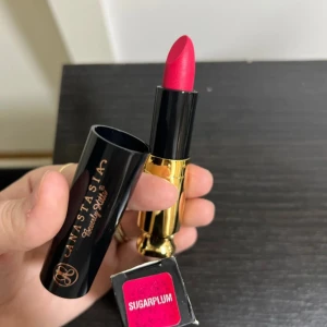 Anastasia Beverly Hills läppstift Sugarplum - Läppstift från Anastasia Beverly Hills i färgen Sugarplum, en intensiv och djup rosa nyans. Snygg svart och guldig hylsa med elegant design. Perfekt för dig som vill ha en färgstark look och lyxig känsla.