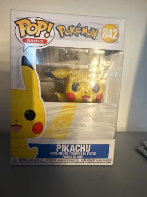 Funko Pop! Games Pokémon Pikachu #842 - Säljer en Funko Pop! Games Pokémon Pikachu #842 vinylfigur i originalförpackning. Figuren är helt ny och oöppnad, med kartongen i mycket fint skick utan synligt slitage. Perfekt för samlare och Pokémon-fans!