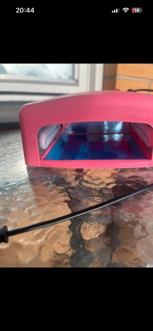 UV-lampa för naglar, rosa - Rosa UV-lampa för naglar med timerfunktion (120 sekunder) och kontinuerligt läge. Perfekt för gel- och shellacmanikyr hemma. Lampan är i gott skick med mindre ytliga repor, fungerar med vanlig stickkontakt. Helt ny oanvänd 