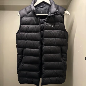  Sail Racing väst  - Snygg svart väst från Sail Racing. Västen är i ett bra skick och storleken står att den är 170 men är S