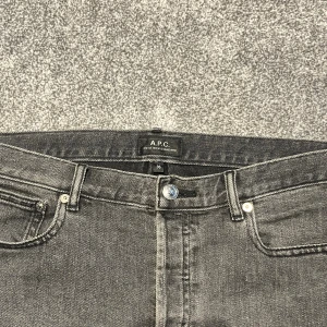Grå jeans från A.P.C. Petit New Standard - Säljer ett par grå jeans från A.P.C. Petit New Standard med klassisk femficksdesign och raka ben. Jeansen har en snygg tvättad finish och silverfärgade detaljer vid knappar och nitar. Perfekt för dig som gillar stilrena och tidlösa jeans.