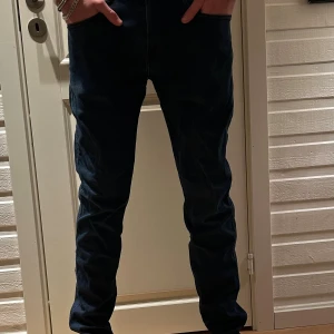 Replay anbass jeans - Säljer ett par mörkblå jeans med skinny passform. Byxorna har klassisk femficksdesign och sitter tajt längs benen. Materialet är jeans och färgen är djup mörkblå, perfekt för dig som gillar en smal siluett. Storlek 32/32
