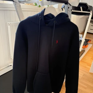 Svart hoodie från Polo Ralph Lauren - Svart hoodie från Polo Ralph Lauren med klassisk röd broderad logga på bröstet. Storlek M och L, köpt för 800 spänn i spanien, otroglig bra kvalite och använd mindren 2 gng. Färg, mörk blå