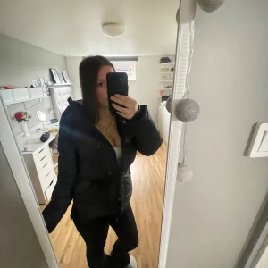 Svart dunjacka Boomerang  - Säljer en svart dunjacka från Boomerang, modell The Authentic 7035 Classic Down Jacket. Jackan har lång ärm, dragkedja och knappar framtill samt en liten broderad logga på ärmen. Perfekt för kalla dagar och har en schysst puffad look. Nypris 6999kr 