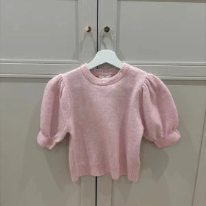Ljusrosa stickad tröja Gina Tricot - Supersöt ljusrosa stickad tröja från Gina Tricot med puffiga korta ärmar och ribbade muddar. Tröjan har rund hals och är perfekt för dig som gillar en gullig och trendig look. Mjuk och skön kvalitet som passar till många olika outfits.