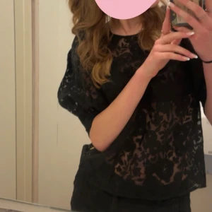 Svart blommig spetsblus - Säljer en svart blus med blommigt spetsmönster. Blusen är lätt transparent och har korta puff ärmar med avslappnad passform. Perfekt för alla tillfällen skola,fest eller middag. Kontakt för fler bilder