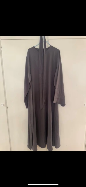Abaya / klänning - Jag bär storlek s/m och den passar mig perfekt. Grå abaya, med ett knytband runt mitten. 